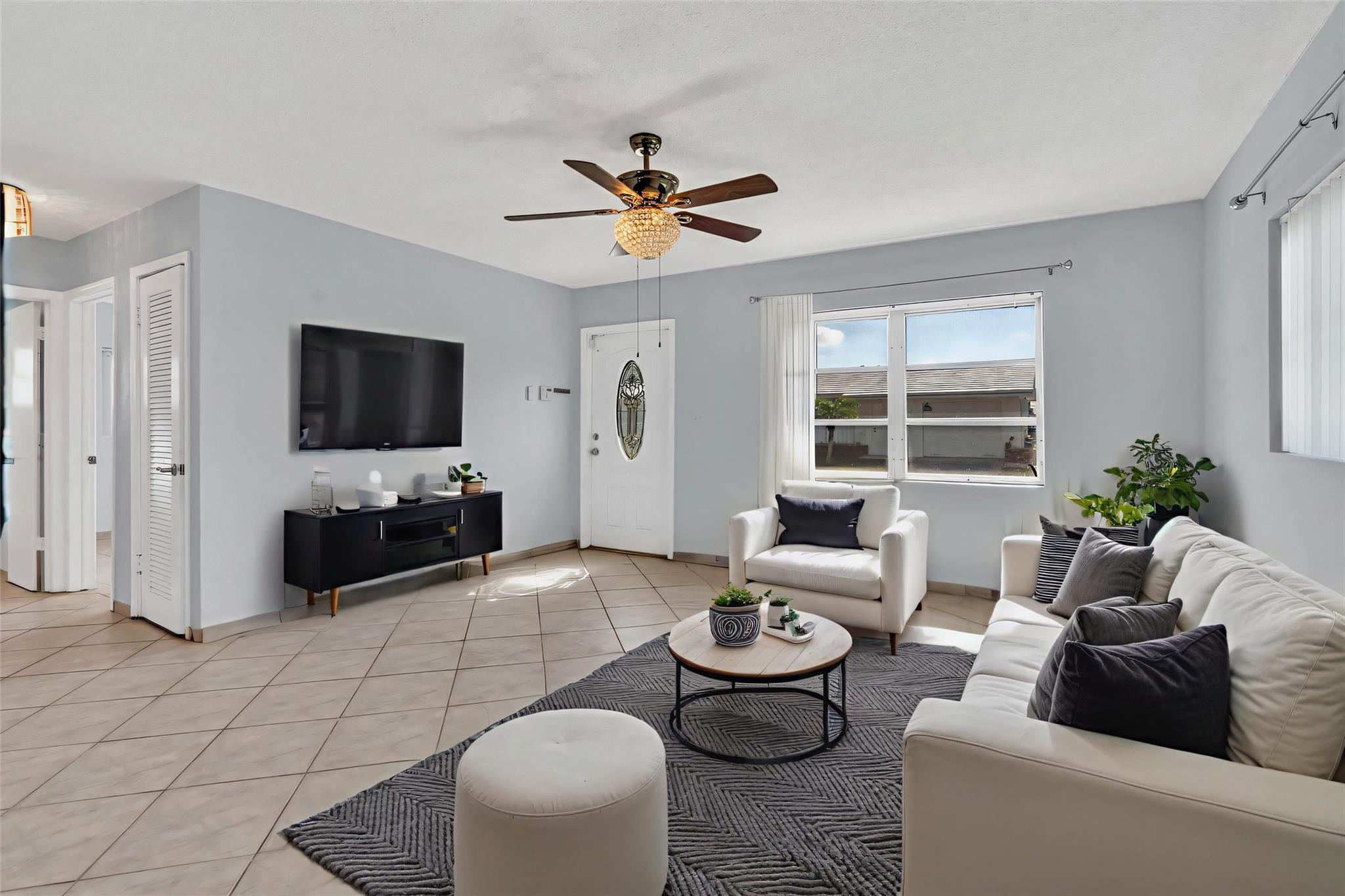 7115 Northwest 73rd Street Tamarac, FL 33321 - Photo 5 of 46 a living room with furniture a flat screen tv and a large window