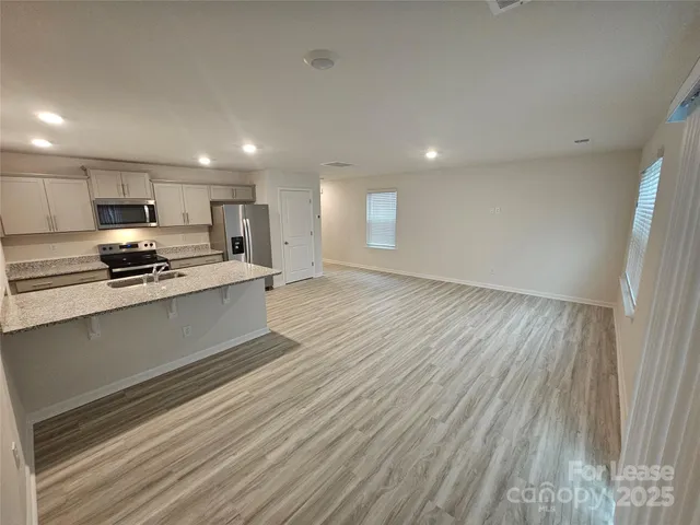 a kitchen with stainless steel appliances kitchen island granite countertop a stove a sink and a refrigerator