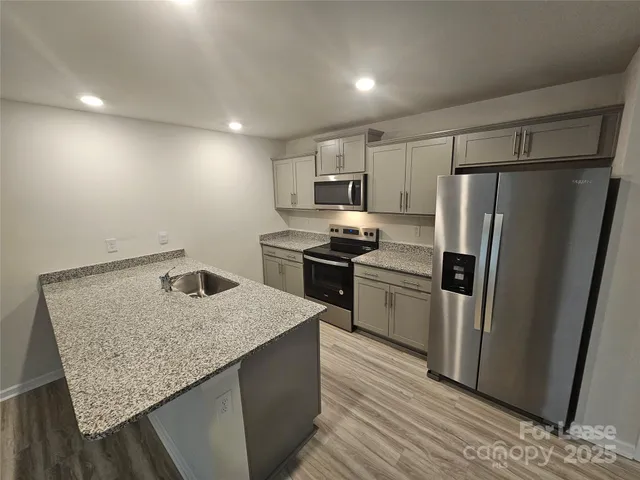 a kitchen with kitchen island granite countertop a sink stove and refrigerator
