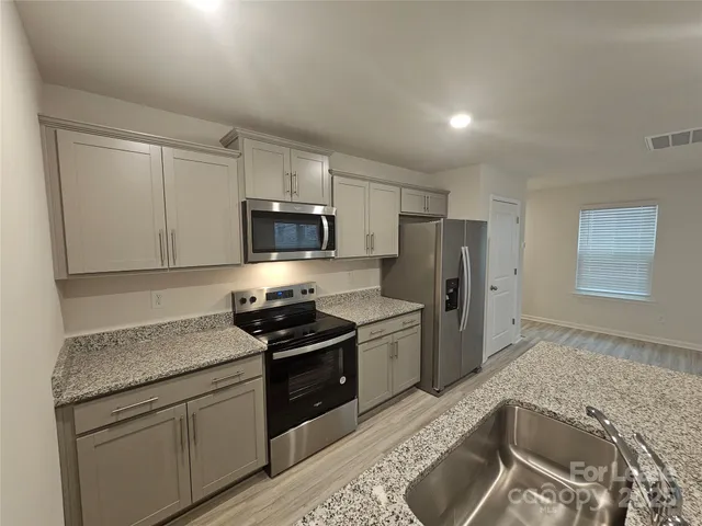 a kitchen with granite countertop stainless steel appliances a stove sink and microwave