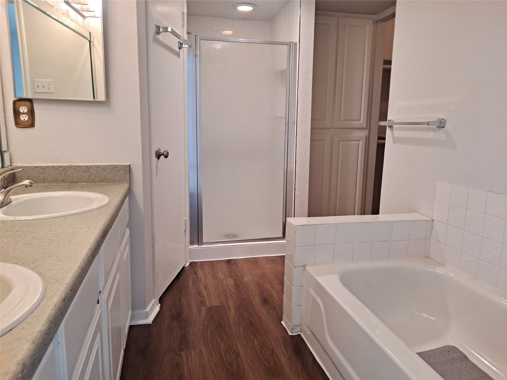 2018 West Rundberg Lane, Unit 9B Austin, TX 78758 - Photo 16 of 23 Full bath featuring a stall shower, a bath, dark wood-type flooring, and double vanity
