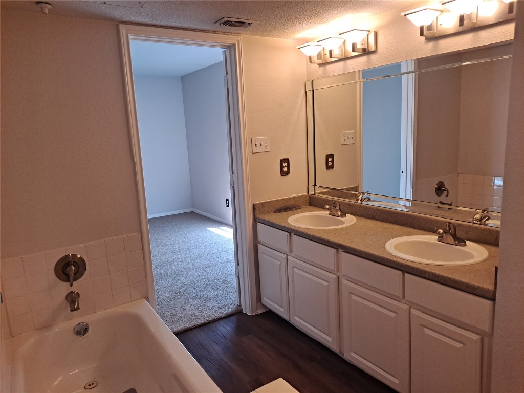 2018 West Rundberg Lane, Unit 9B Austin, TX 78758 - Photo 17 of 23 Full bath with double vanity, a garden tub, a textured ceiling, and dark wood finished floors