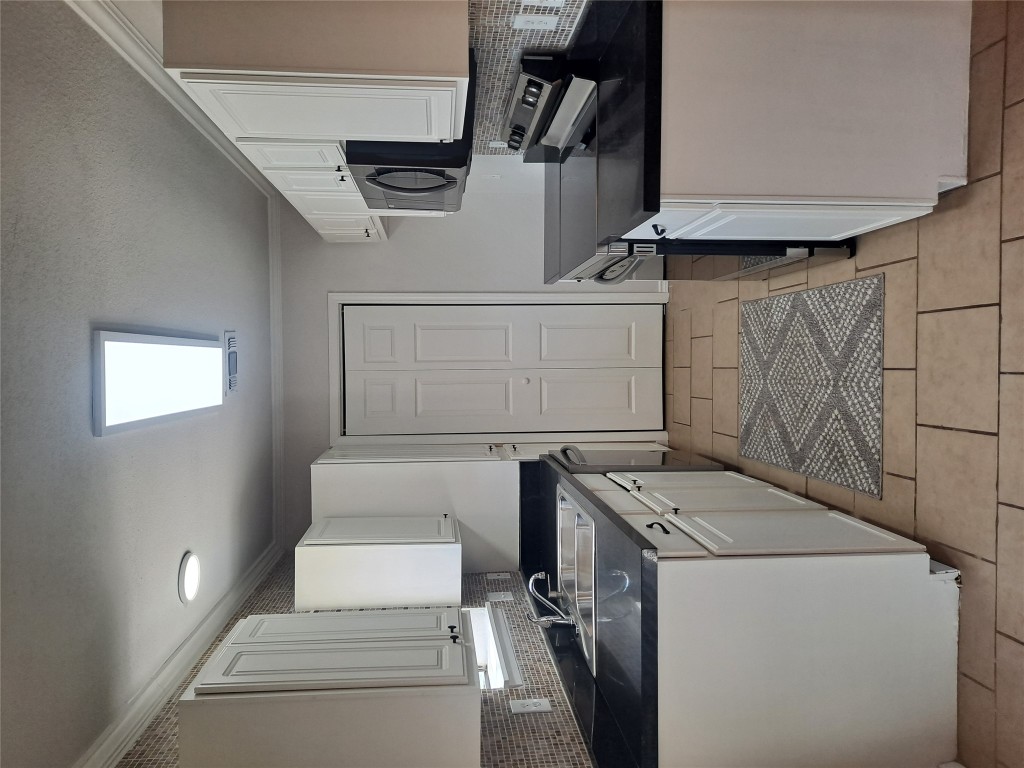 2018 West Rundberg Lane, Unit 9B Austin, TX 78758 - Photo 3 of 23 Kitchen with backsplash, stove, crown molding, white cabinetry, and dark countertops