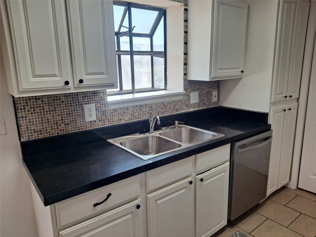 2018 West Rundberg Lane, Unit 9B Austin, TX 78758 - Photo 5 of 23 Kitchen with dark countertops, white cabinetry, dishwasher, and light tile patterned flooring