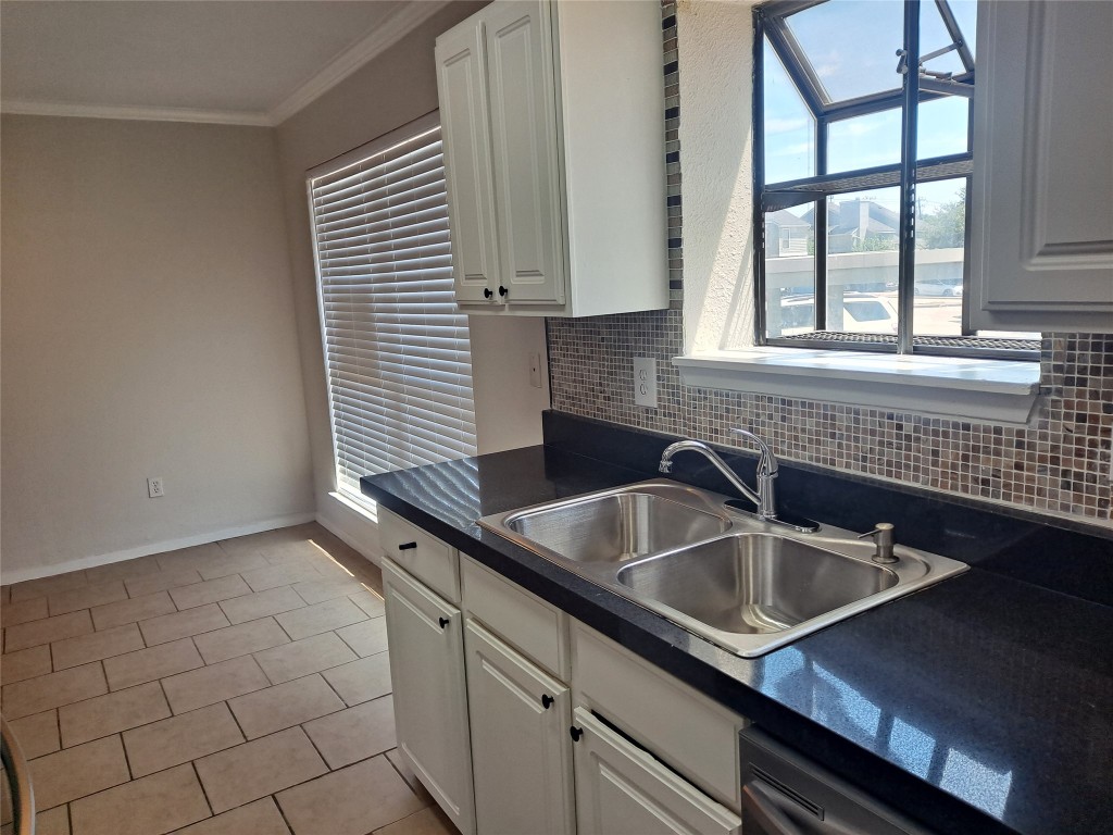 2018 West Rundberg Lane, Unit 9B Austin, TX 78758 - Photo 6 of 23 Kitchen with dark countertops, crown molding, tasteful backsplash, white cabinetry, and light tile patterned floors