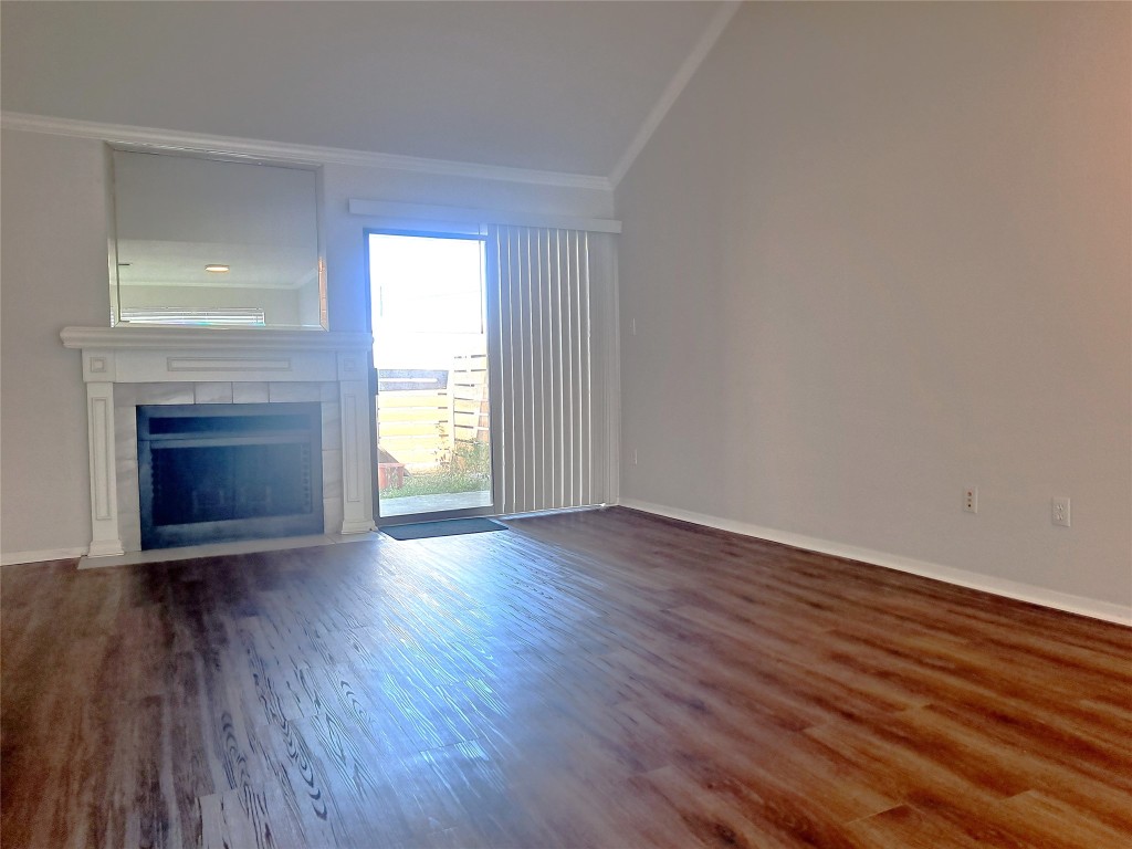2018 West Rundberg Lane, Unit 9B Austin, TX 78758 - Photo 8 of 23 Unfurnished living room featuring dark wood-style flooring, a fireplace, and ornamental molding