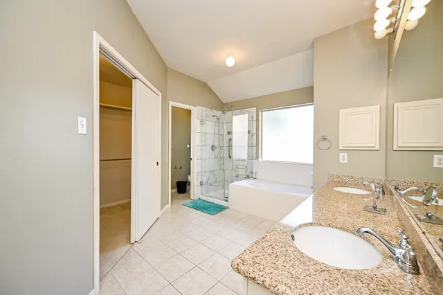 a spacious bathroom with a granite countertop tub sink shower and mirror