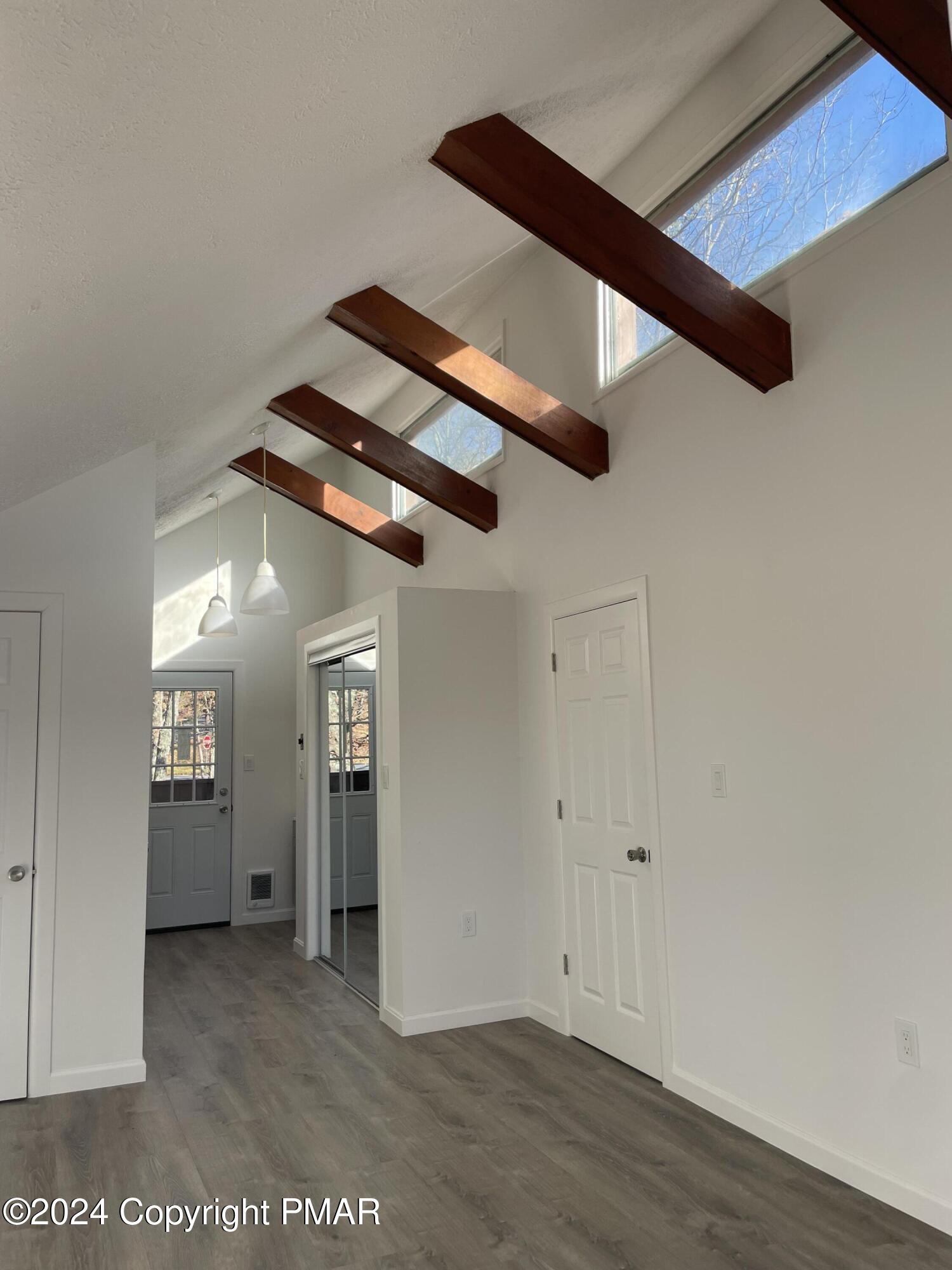 2204 Exeter Court Bushkill, PA 18324 - Photo 16 of 29 an empty room with wooden floor windows and kitchen view
