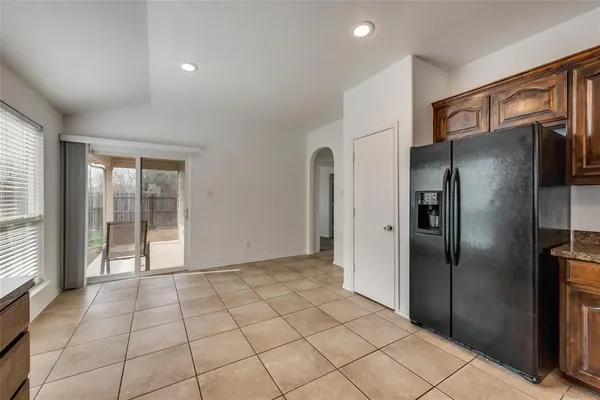 a view of a refrigerator in kitchen and an empty room