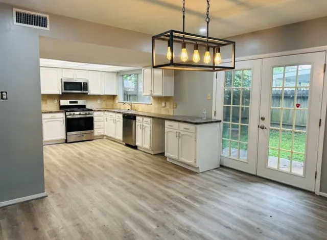 a kitchen with stainless steel appliances granite countertop a stove and a wooden floors