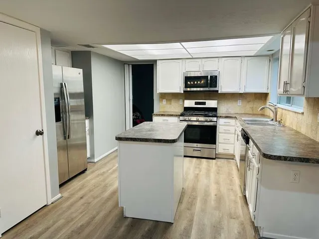 a kitchen with stainless steel appliances granite countertop a refrigerator a stove and a sink