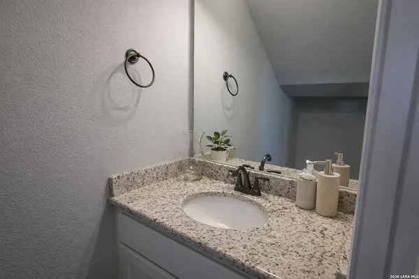 a bathroom with a granite countertop sink and a mirror
