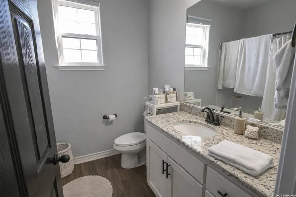 a bathroom with a granite countertop sink toilet and mirror
