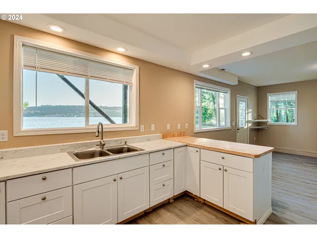 a large white kitchen with a sink and dishwasher a stove with wooden floor