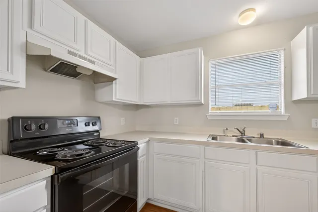 a kitchen with stainless steel appliances granite countertop white cabinets and a stove top oven