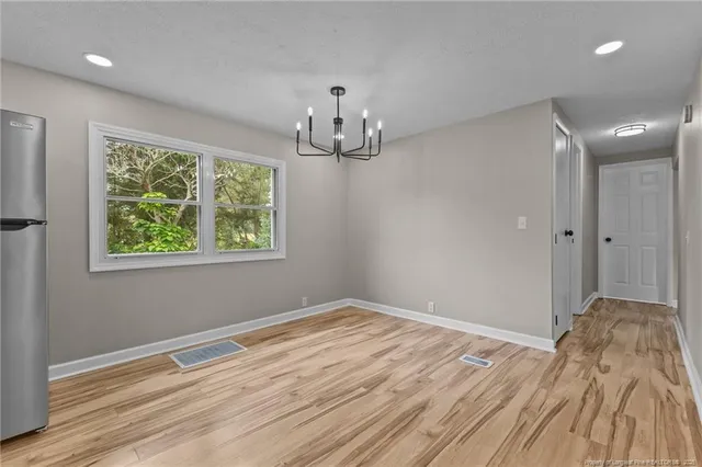 a view of empty room with wooden floor and window