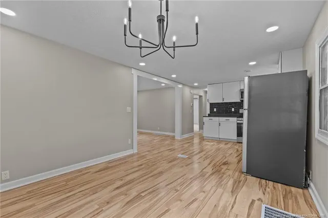 a view of kitchen and empty room with wooden floor