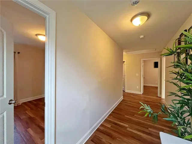 a view of a hallway with wooden floor and a bathroom