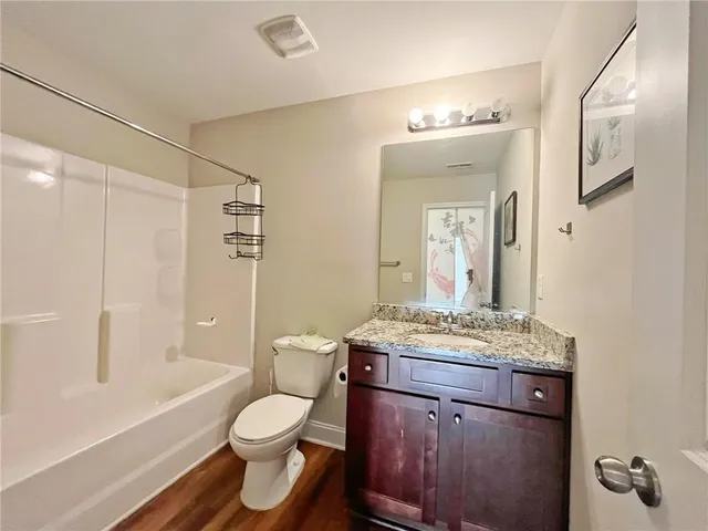 a bathroom with a granite countertop sink toilet a large mirror a shower and a bathtub