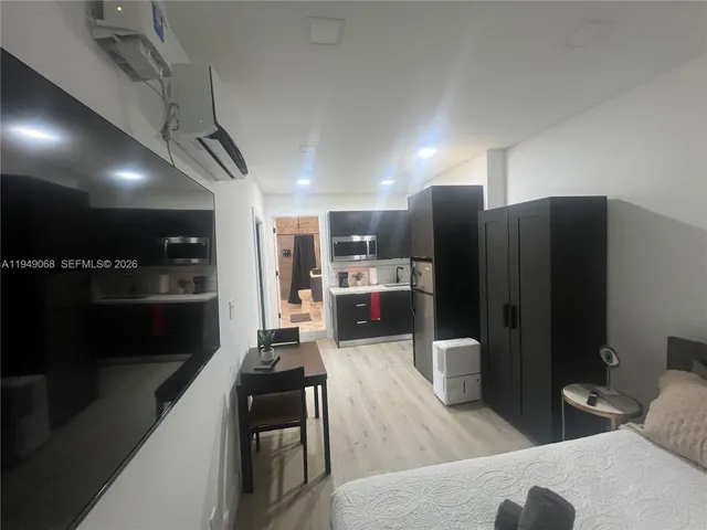 a open kitchen with stainless steel appliances kitchen island granite countertop a refrigerator a stove and a sink with wooden floor