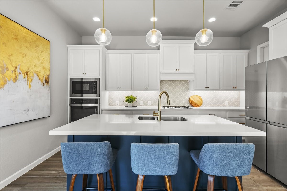 4910 Morrison Drive Manvel, TX 77578 - Photo 2 of 35 a kitchen with a sink a stove a kitchen island and chairs with wooden floor