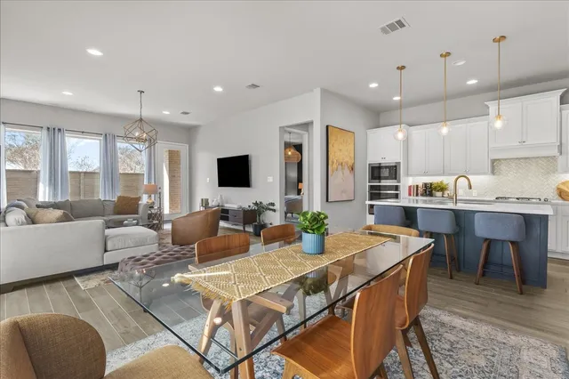 a living room with stainless steel appliances kitchen island granite countertop a dining table chairs kitchen view and a window