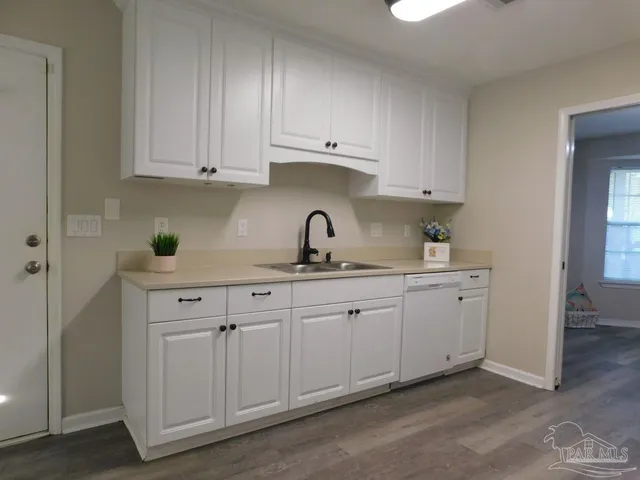 a kitchen with white cabinets and sink