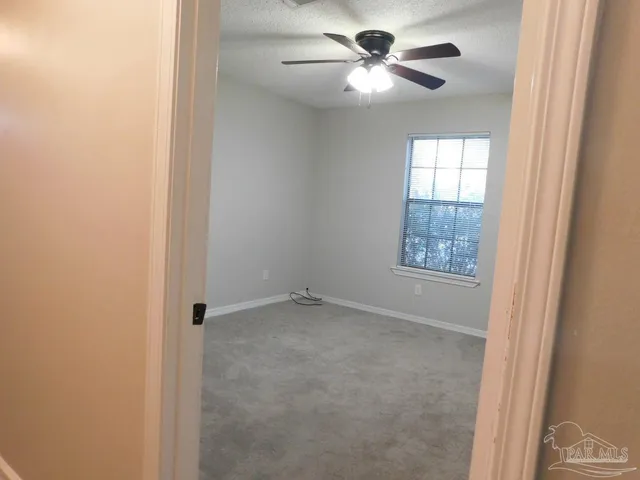 an empty room with windows and fan