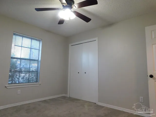 an empty room with windows and fan