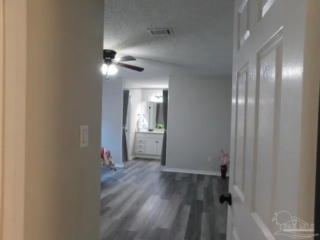 a view of a hallway with wooden floor and a bathroom