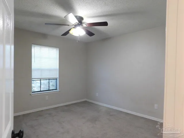 an empty room with windows and fan