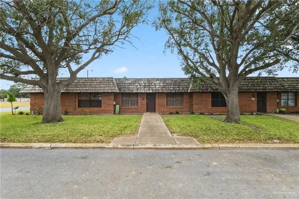 a view of a house with a yard and large tree