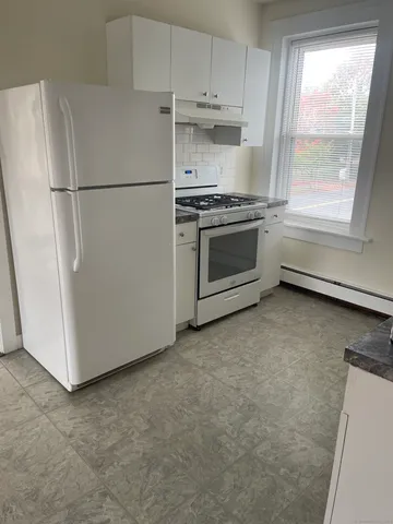 a white refrigerator freezer and a stove sitting inside of a kitchen