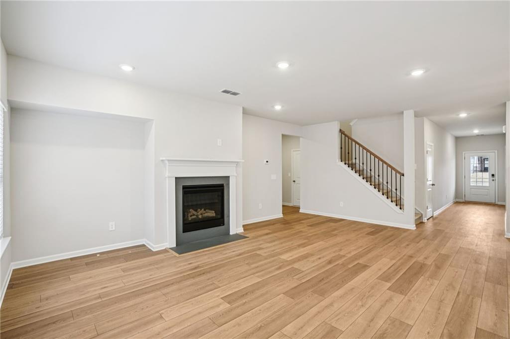 6939 Winchester Place Fairburn, GA 30213 - Photo 11 of 56 a view of an empty room with wooden floor fireplace and a window