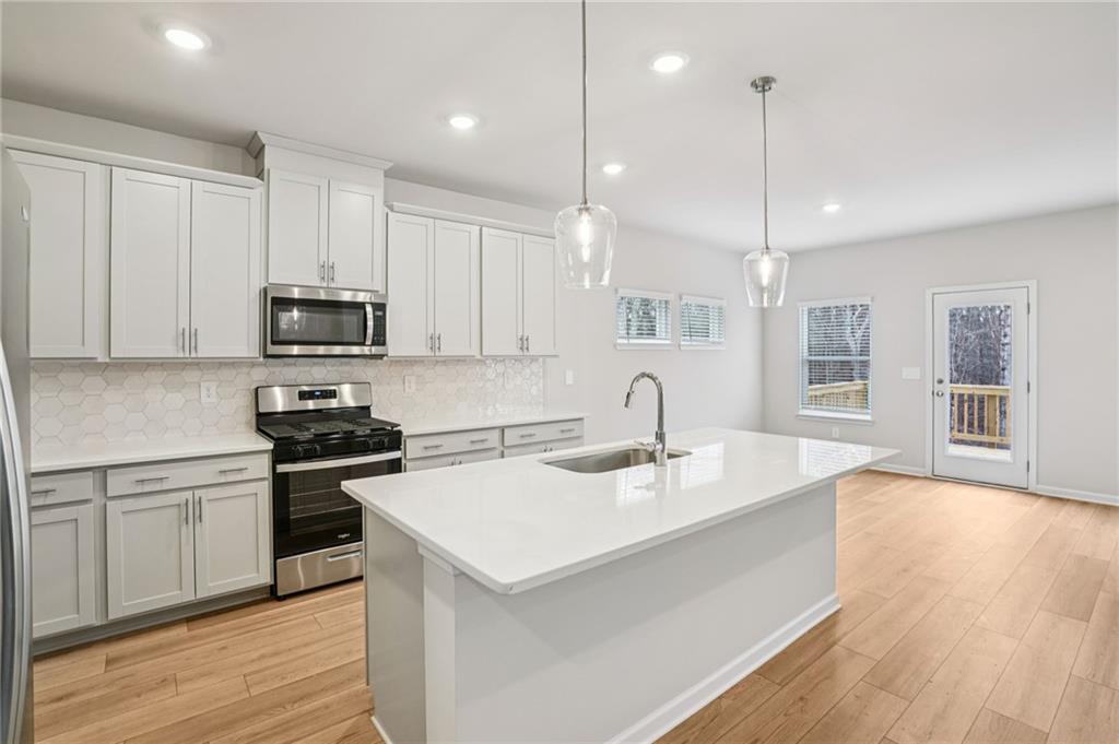 6939 Winchester Place Fairburn, GA 30213 - Photo 12 of 56 a kitchen with stainless steel appliances granite countertop a sink a stove and kitchen island