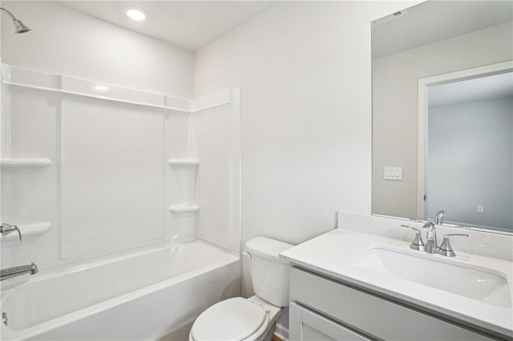 6939 Winchester Place Fairburn, GA 30213 - Photo 39 of 56 a bathroom with a granite countertop sink toilet a mirror and a bathtub