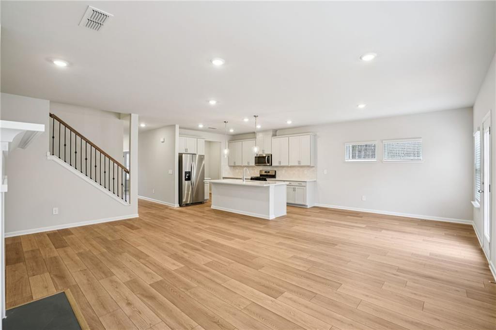 6939 Winchester Place Fairburn, GA 30213 - Photo 10 of 56 a view of an empty room with wooden floor and a kitchen