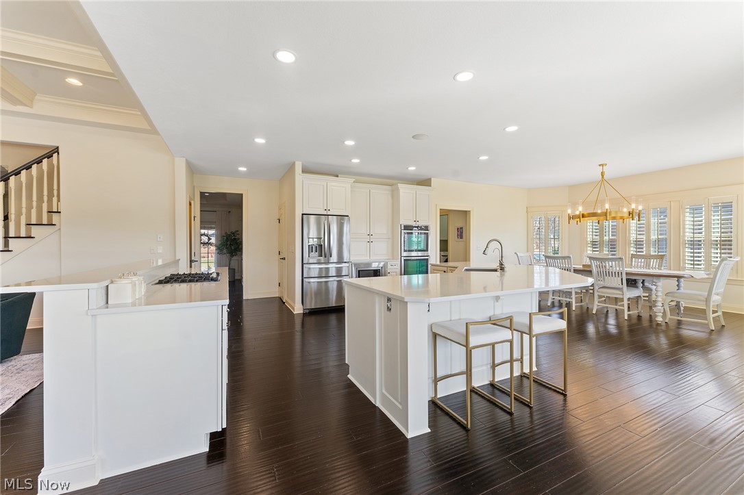 6716 Kyle Ridge Pointe Canfield, OH 44406 - Photo 7 of 43 Kitchen featuring pendant lighting, an inviting chandelier, stainless steel appliances, dark wood-type flooring, and a kitchen bar