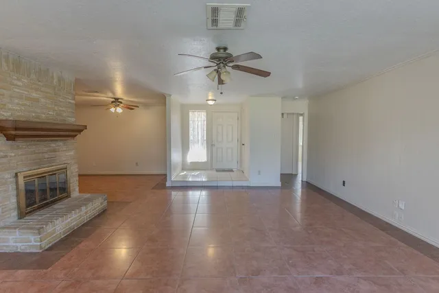 an empty room with wooden floor fireplace and fan