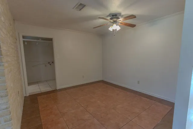 an empty room with a chandelier fan and windows