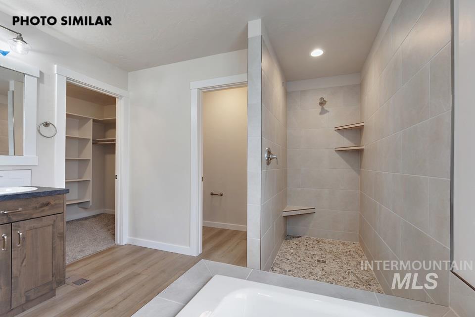 1645 Haystack Emmett, ID 83617 - Photo 17 of 33 Walk-in shower with light-toned rectangular wall tiles, a river rock floor, and built-in corner shelving