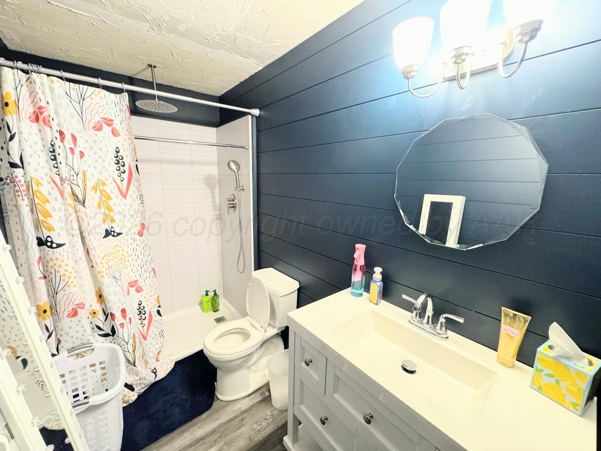 1413 South Harvard Street Perryton, TX 79070 - Photo 7 of 14 a bathroom with a sink mirror vanity and toilet