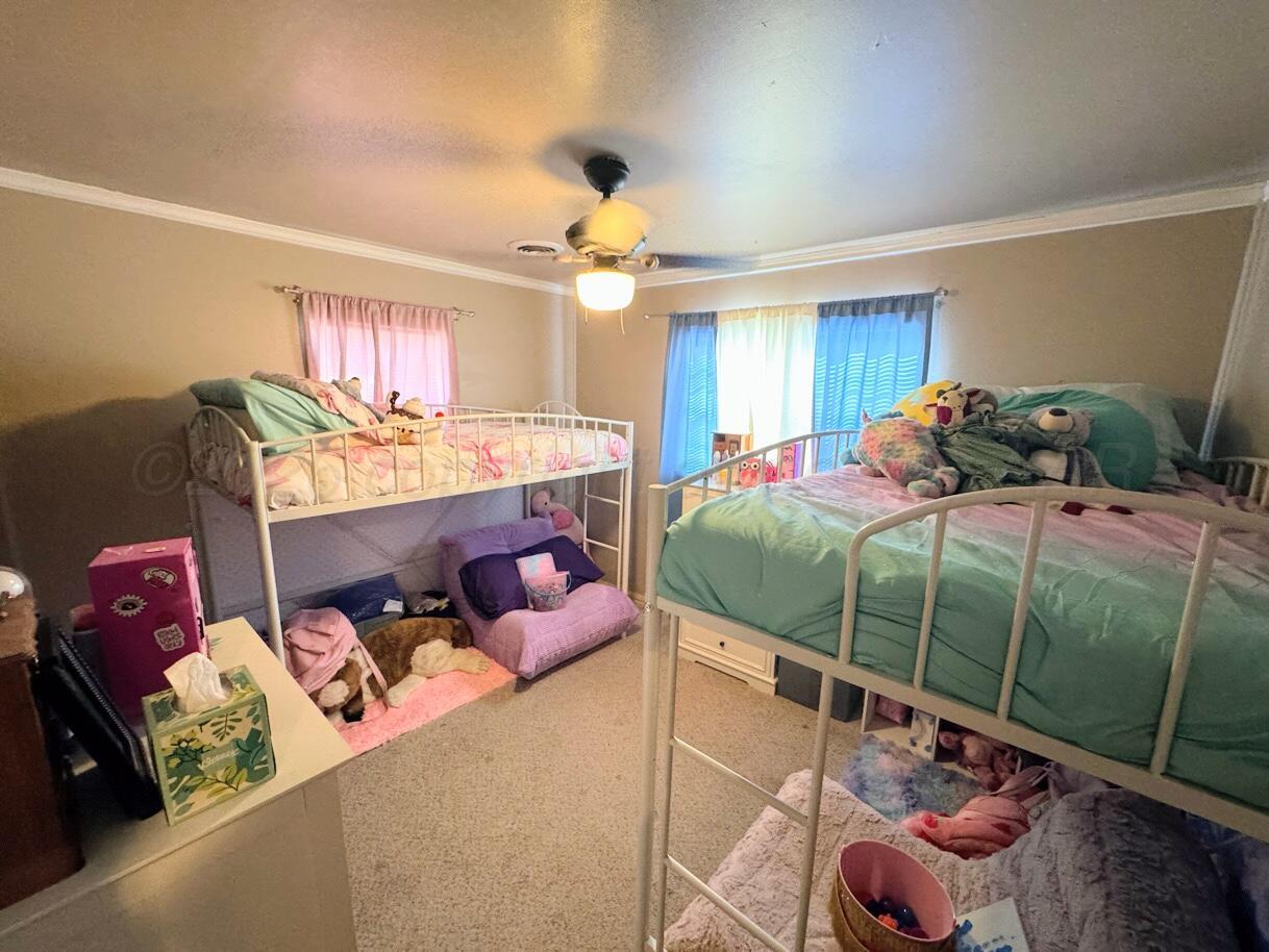 1413 South Harvard Street Perryton, TX 79070 - Photo 9 of 14 a bedroom with a bed and a chandelier