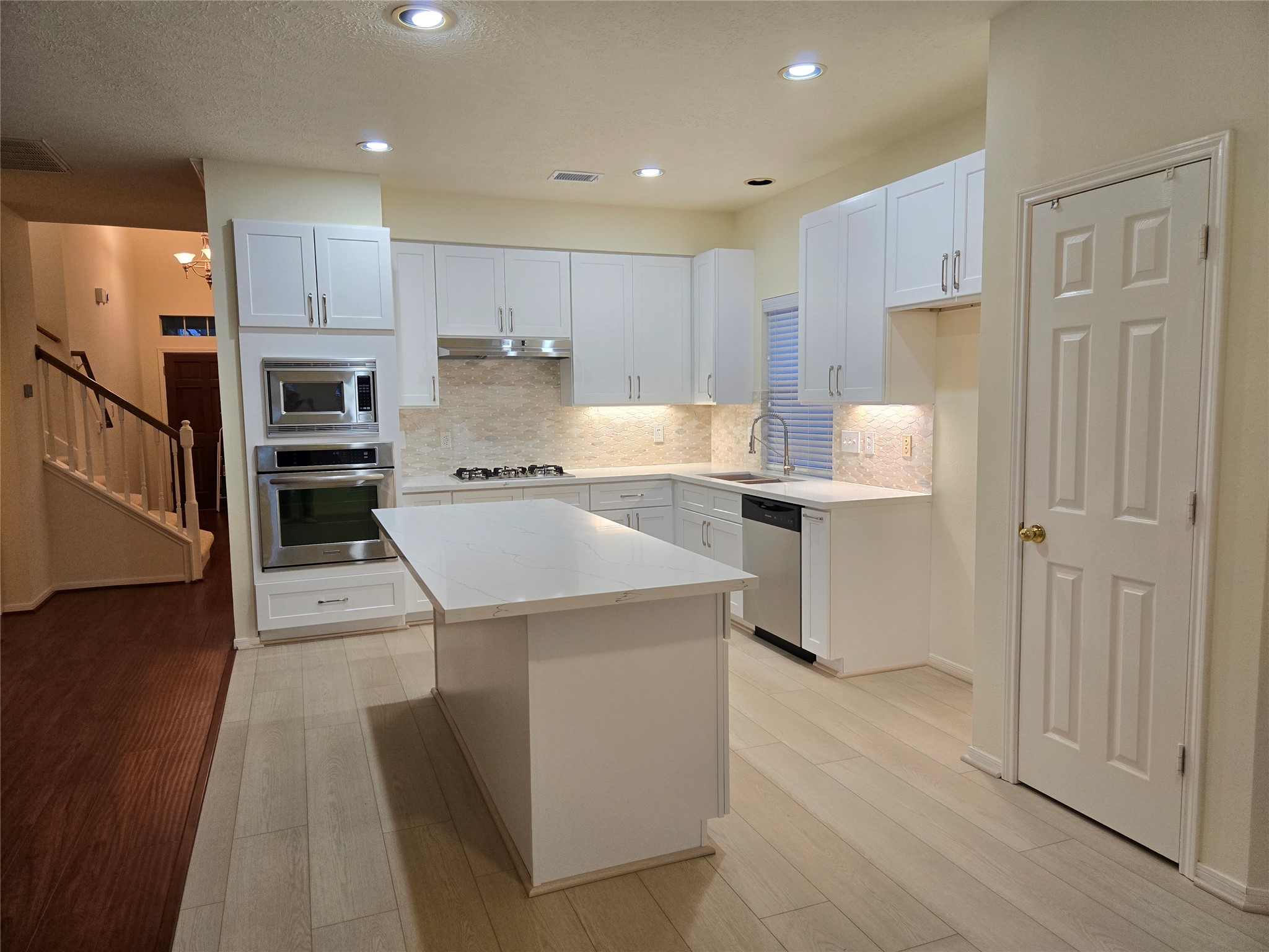 3138 Waters Way Drive Sugar Land, TX 77478 - Photo 19 of 42 a kitchen with a sink a refrigerator a stove and white cabinets with wooden floor