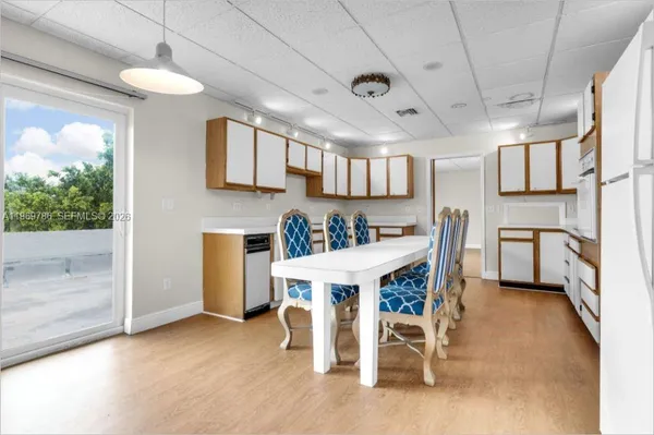 a kitchen with stainless steel appliances kitchen island granite countertop a table chairs sink and cabinets