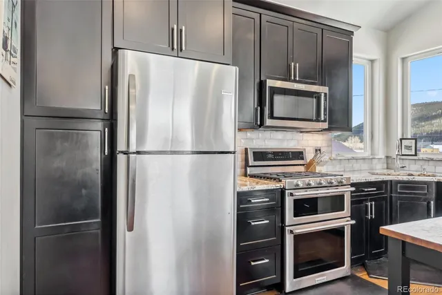 a kitchen with stainless steel appliances granite countertop a refrigerator stove a sink and a microwave