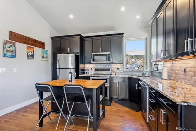 a kitchen with stainless steel appliances granite countertop a table chairs sink refrigerator and microwave