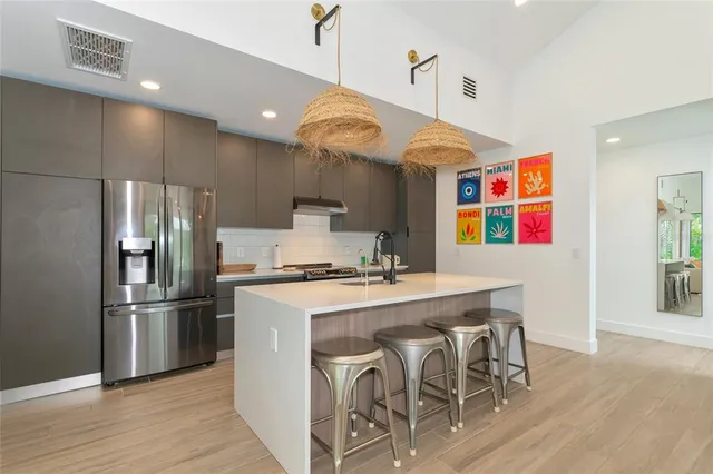 a kitchen with stainless steel appliances granite countertop a stove a refrigerator a oven a sink with a dining table and chairs