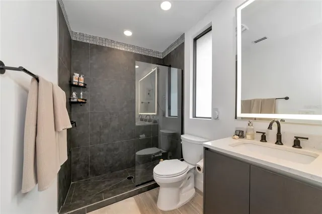 a bathroom with a shower sink vanity mirror and toilet