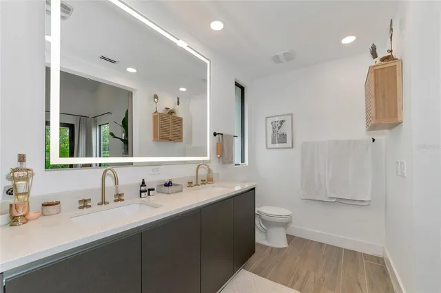 a bathroom with a double vanity sink mirror and toilet